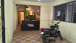 A reception area with a checkered floor, a reception desk, a motorcycle, and a window with bars. - Balaji Lodging  (Hinjawadi)