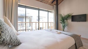 A hotel room with a bed, a TV, a balcony, and a plant. - Tabi・Stay KOHAMA｜Direct train access to popular shopping areas such as Tennoji Park (Osaka)