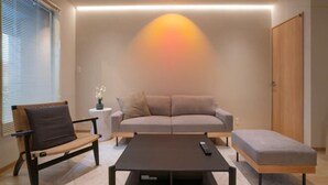 A modern living room with a sofa, a bench, a coffee table, and a TV. - Tabi・Stay KOHAMA｜Direct train access to popular shopping areas such as Tennoji Park (Osaka)
