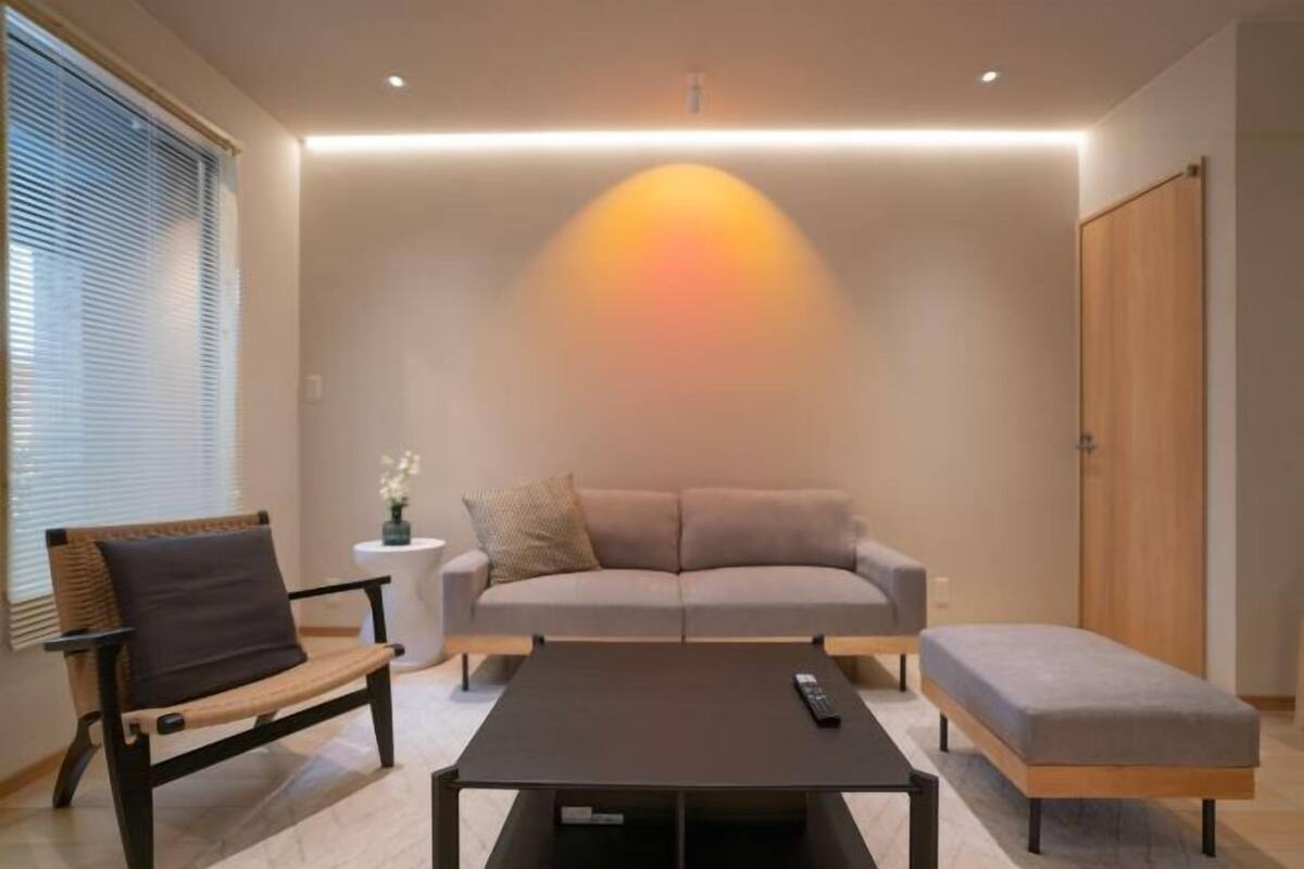Ein modernes Wohnzimmer mit einer Couch, einer Bank, einem Couchtisch und einem Fernseher.