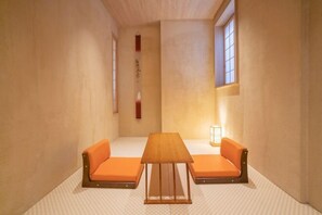 A minimalist room with a wooden table and orange cushioned seating.