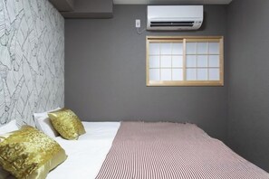 A bedroom with a bed, pillows, a window, and an air conditioning unit. - Silent Echo Inn (Osaka)