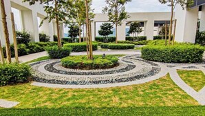 A landscaped courtyard with a circular stone pathway, surrounded by neatly trimmed hedges and trees. - Sunset Lake View at M-Luna Kepong by HCK (Kuala Lumpur)