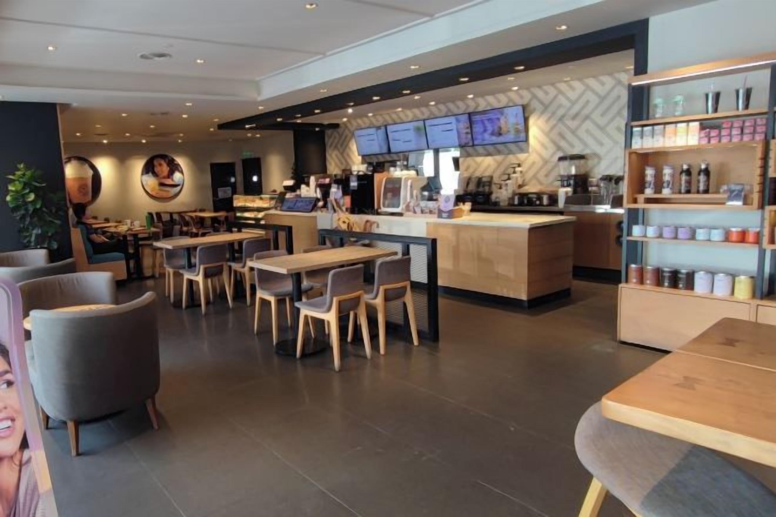 A modern cafe with a counter, seating area, and a display of beverages.