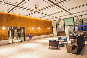 Una hall d'hotel con reception, area salotto e un'ampia finestra.