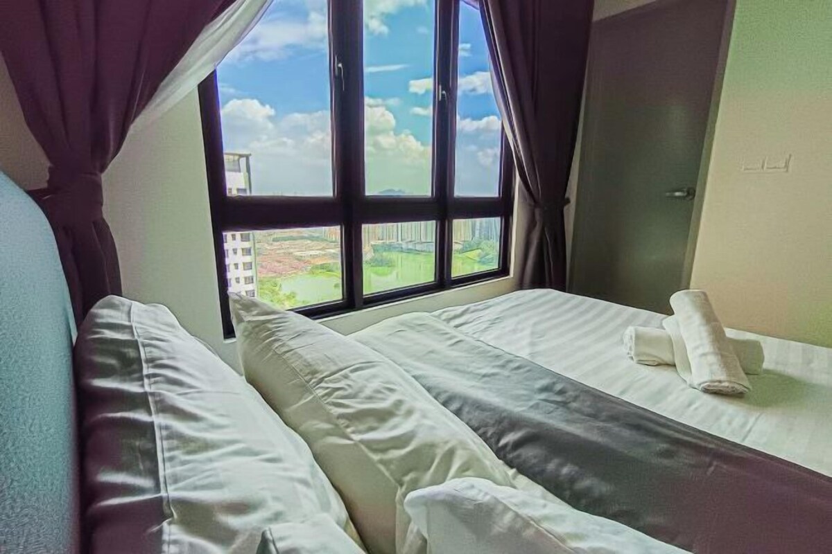 Una habitación de hotel con una cama, un ventanal con cortinas y vistas a edificios.