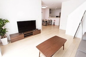 A modern living room with a flat-screen TV, a wooden coffee table, and a grey sofa. - MoonLight inn Free parking (Dazaifu)
