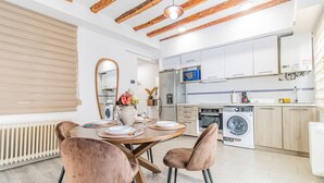 Une cuisine moderne avec des meubles blancs, un four encastré et un lave-linge.