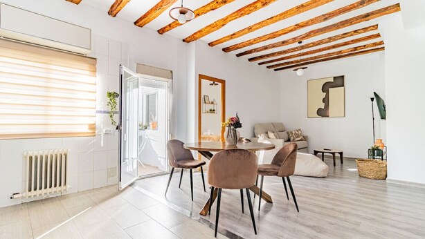 Un salon moderne avec un plafond en bois, un coin repas avec une table ronde et des chaises, et un canapé.