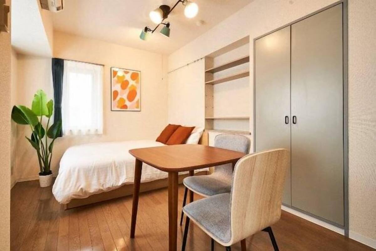 Quarto com cama, mesa, cadeira, guarda-roupa e uma planta.