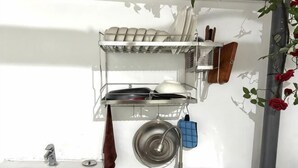A kitchen with a sink, a dish rack, and a hanging pot holder. - HUYNH's HOUSE 4 Bedroom Apartment (Phu Quoc Island)