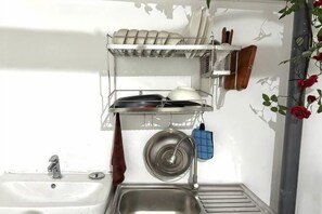 A kitchen with a sink, a dish rack, and a hanging pot holder. - HUYNH's HOUSE 4 Bedroom Apartment (Phu Quoc Island)