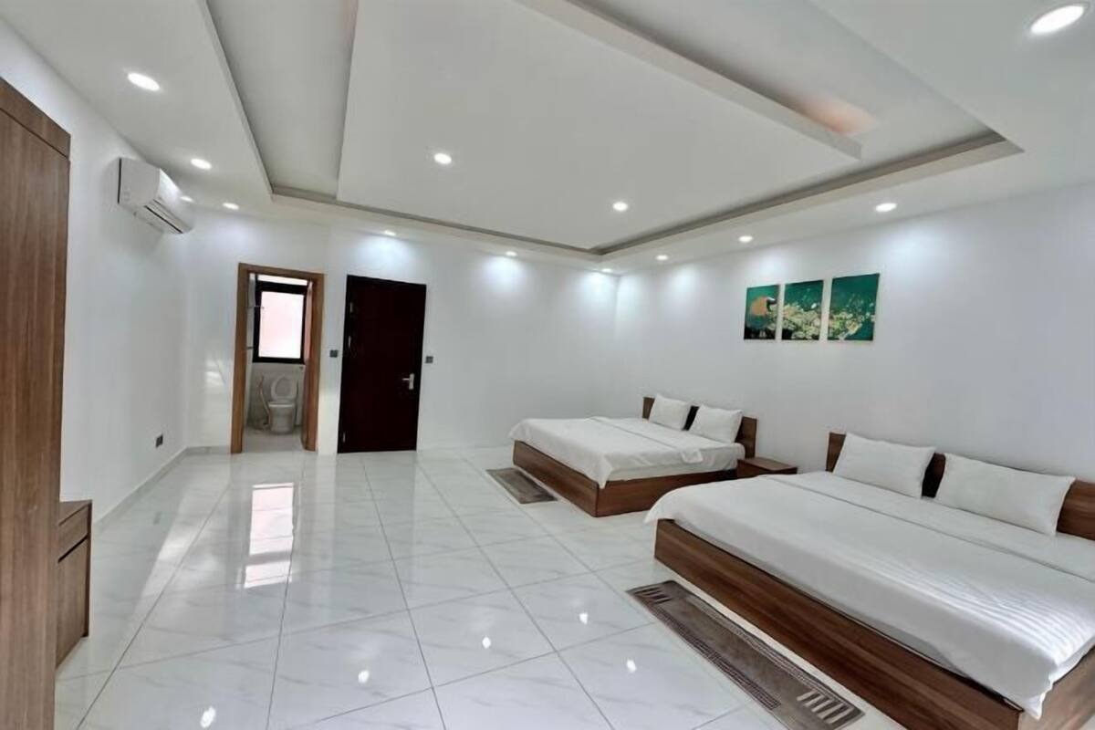 A modern hotel room with a large bed, a separate seating area, and a bathroom visible through an open door.