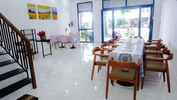 A dining area with a long table, chairs, and a staircase. - HUYNH's HOUSE 4 Bedroom Apartment (Phu Quoc Island)