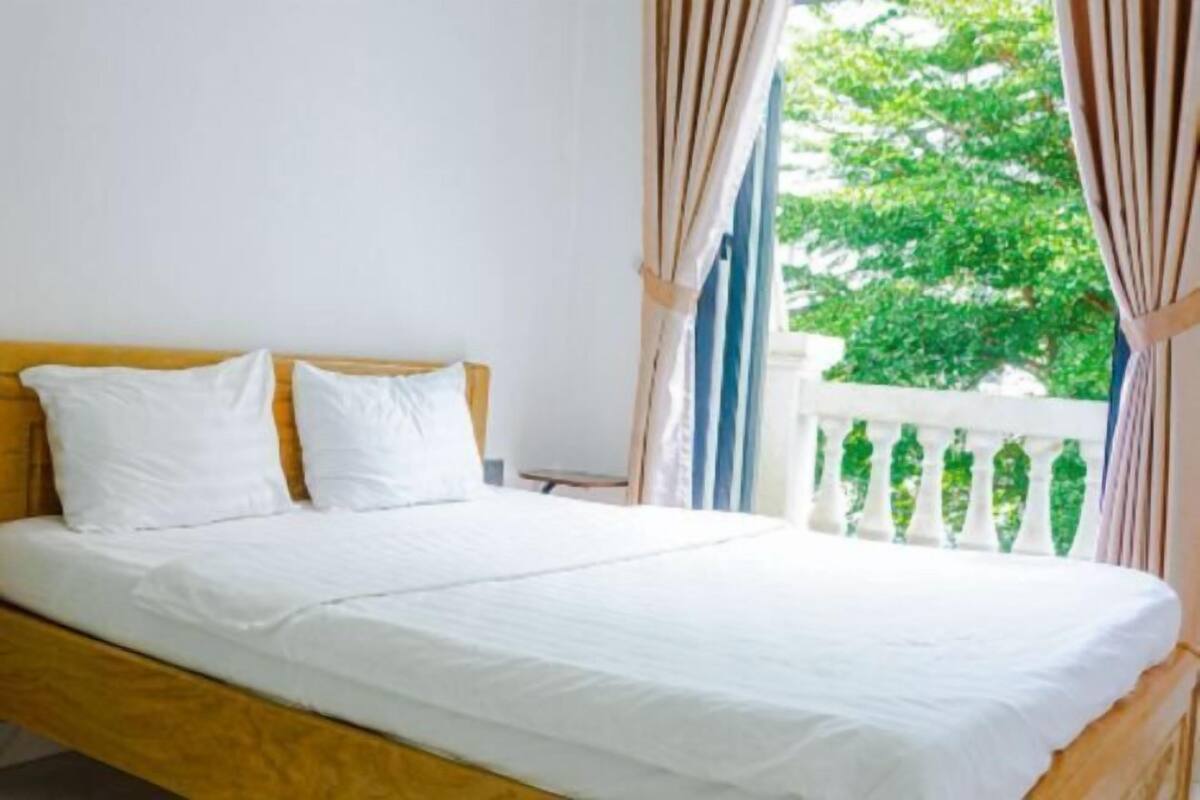 A bed with white bedding, a wooden headboard, and curtains.