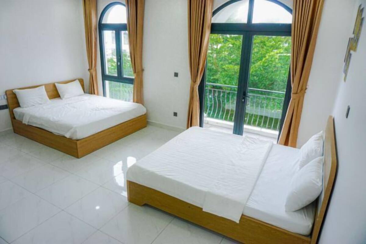 A hotel room with two beds, large windows, and a balcony.