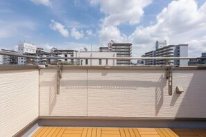 A rooftop terrace with a wooden deck, metal railings, and a view of surrounding buildings. - QingChen zhi Shu (Osaka)