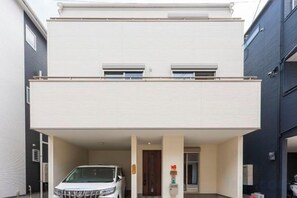 A two-story building with a covered parking area and a white car parked inside. - QingChen zhi Shu (Osaka)