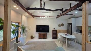 A modern living room with a sofa, a dining table, and a TV.