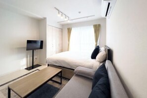 A modern hotel room with a bed, a sofa, a TV, and a desk. - toggle BUNKYO KORAKUEN (Tokyo)