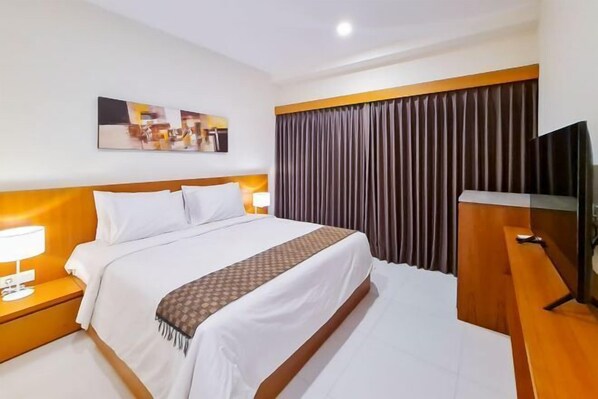 A hotel room with a bed, a TV, a painting on the wall, and a curtain. - Aldan Guest House Syariah (Bali)