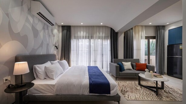A modern hotel room with a large bed, a sofa, a coffee table, and a view of the outdoors. - 22 By Spacey (#55) | Studio in Maadi (Cairo)