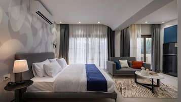 Une chambre d’hôtel moderne, dotée d’un grand lit, d’un canapé, d’une table basse et offrant une vue sur l’extérieur.