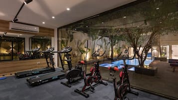 Une salle de sport équipée de tapis de course, de vélos d’appartement et d’un espace piscine.