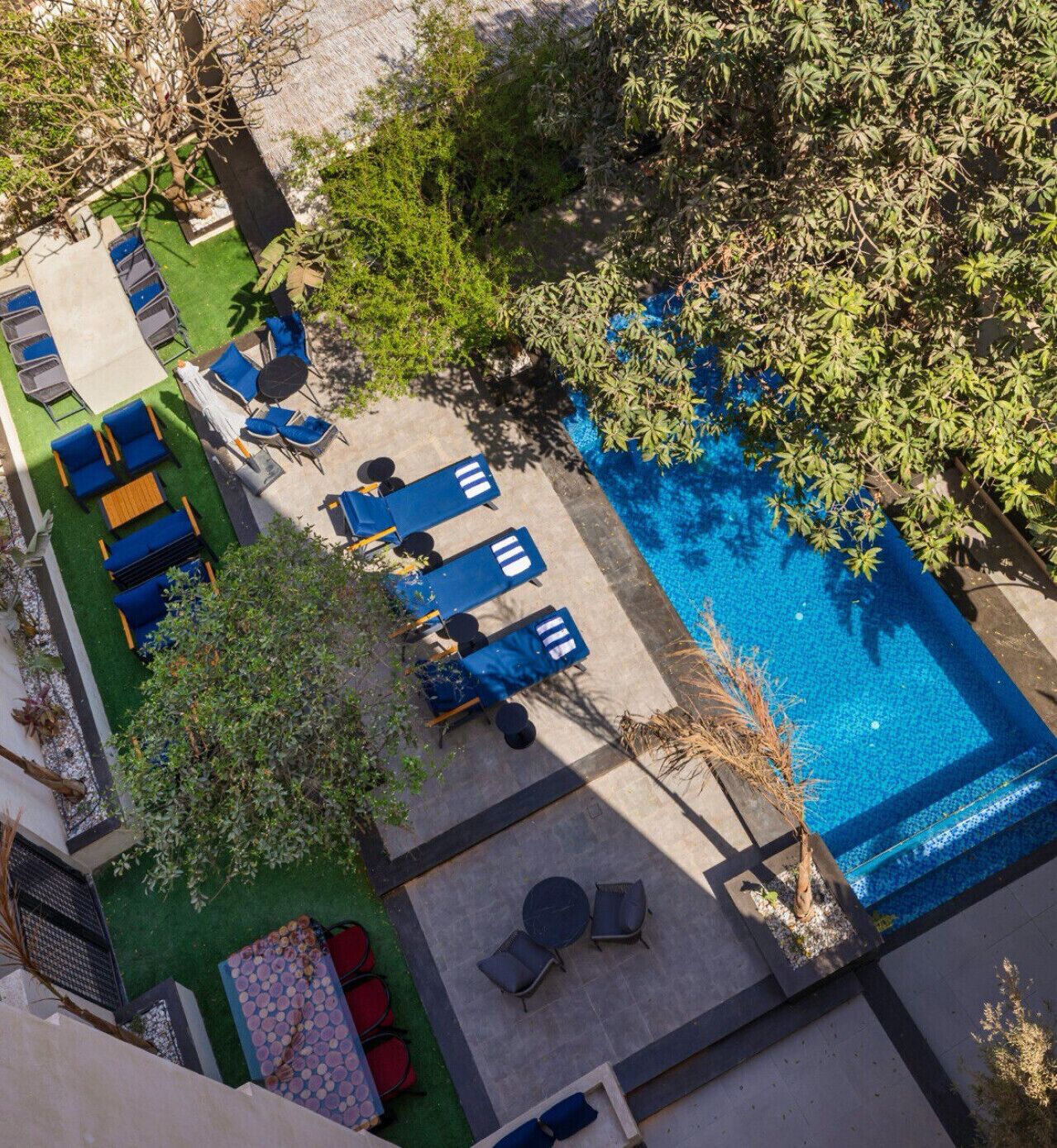 Vue aérienne d’un espace piscine sur le toit, avec plusieurs chaises longues et une piscine.