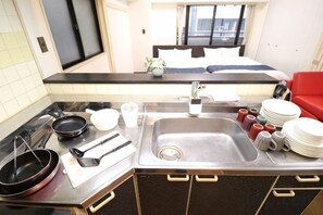 A compact kitchen with a sink, stove, and dining area. - Amistá.You (Osaka)