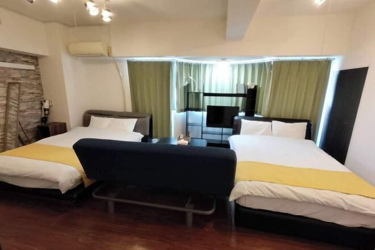 A hotel room with two beds, a small table, a chair, and a TV.