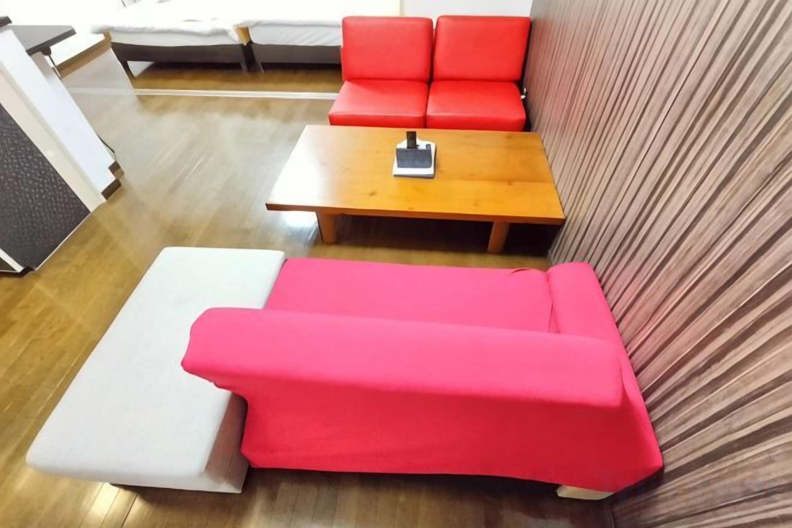 A room with a red sofa, a wooden table, and a white sofa.