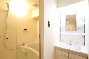 A bathroom with a bathtub, a shower, and a mirror above the sink. - Amistá.You (Osaka)