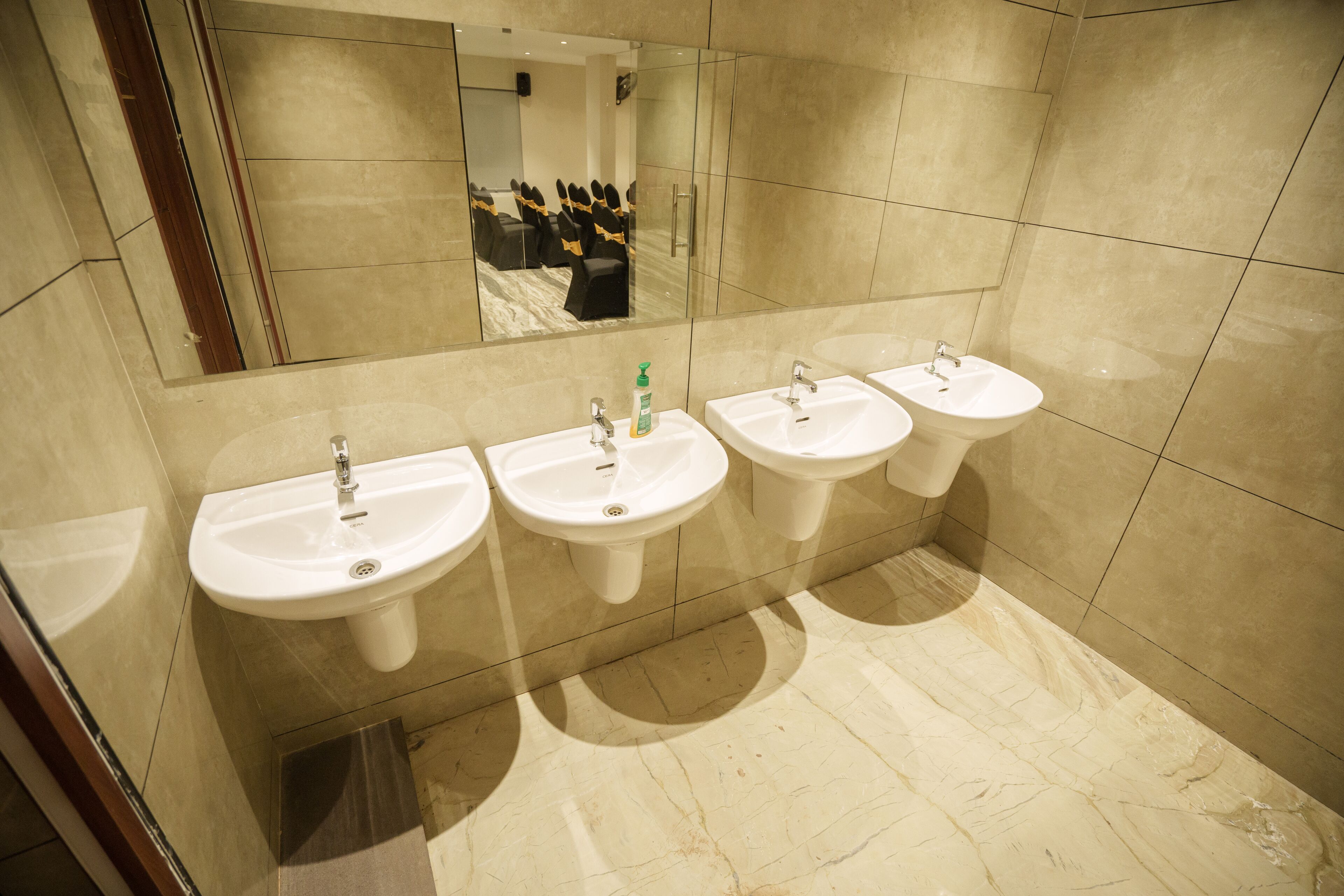 A bathroom with three sinks, a mirror, and a tiled floor.