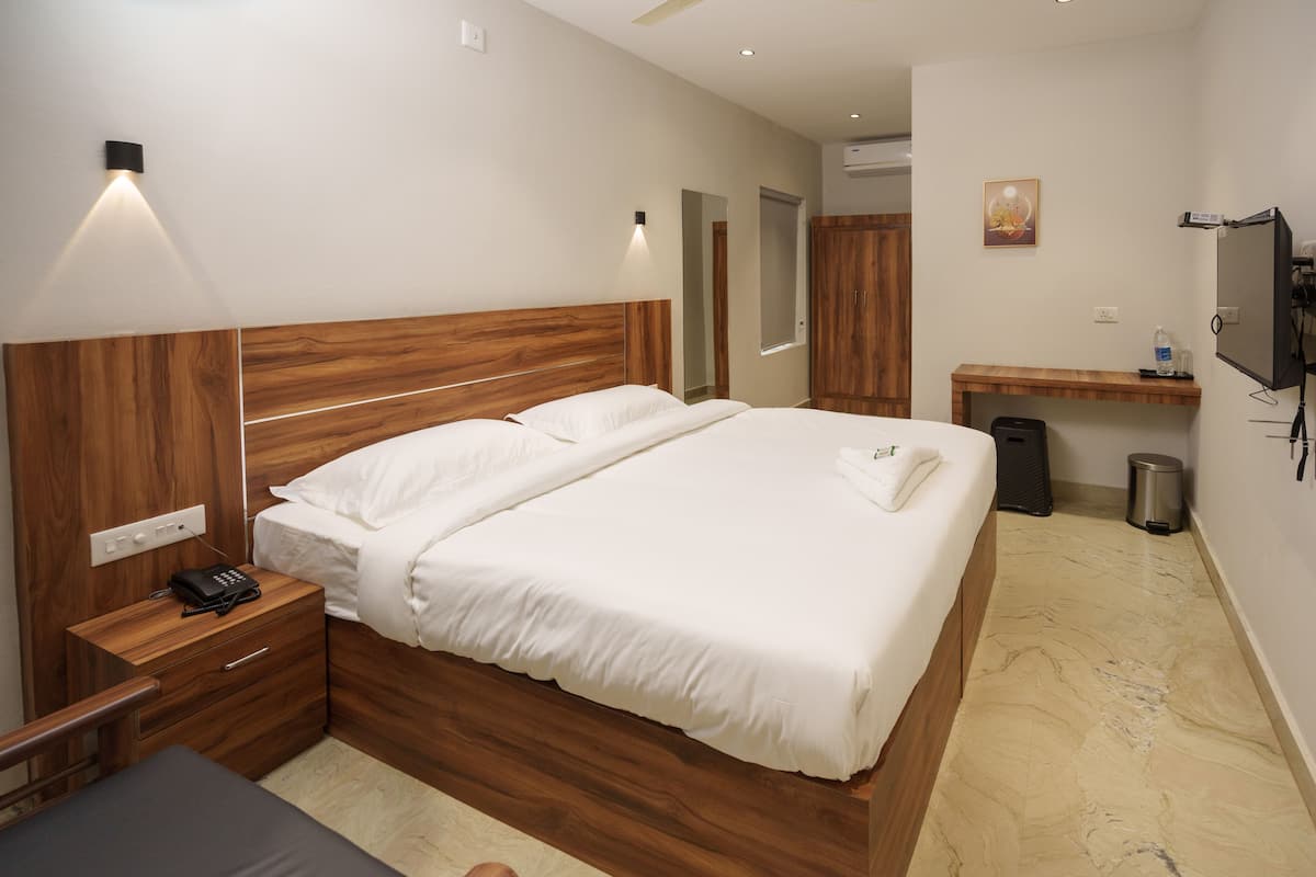 Een moderne hotelkamer met een groot bed, een houten hoofdbord, nachtkastjes, een bureau en een televisie.
