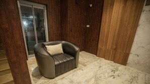 A modern living room with a leather sofa, wooden paneling, and a marble floor. - Kanak Residency Thalassary (Thalassery)