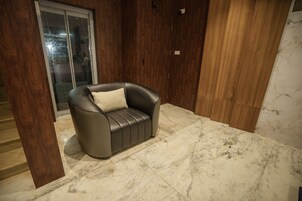 A modern living room with a leather sofa, wooden paneling, and a marble floor.