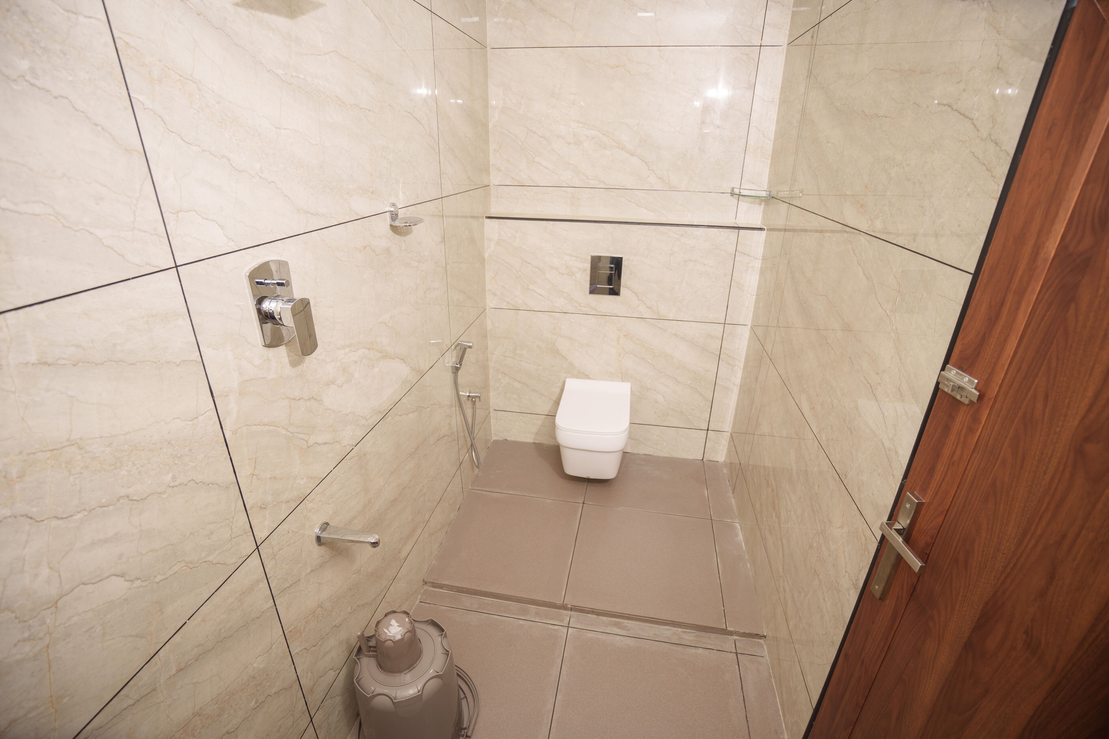 A small, modern bathroom with a toilet, shower, and a trash bin.
