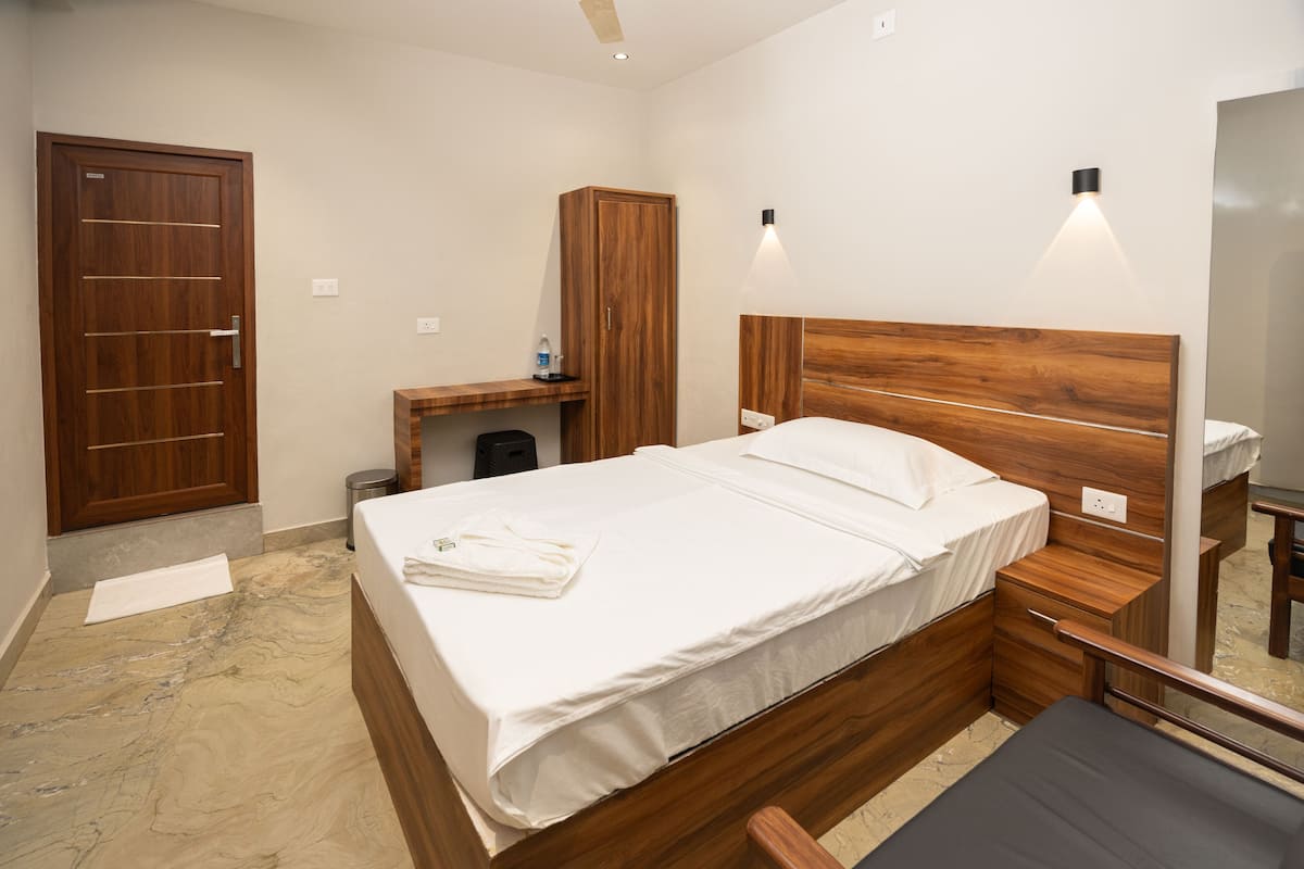 Een slaapkamer met een houten bed, nachtkastje, kledingkast en spiegel.