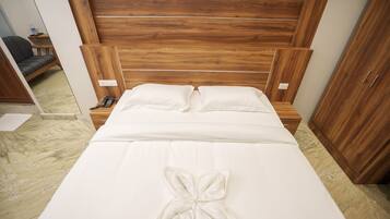 A neatly made bed with a wooden headboard, a bedside table with a lamp, and a wardrobe.
