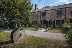 Un edificio de ladrillo con camino de grava, una gran escultura de piedra y un árbol.