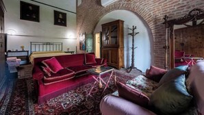 A room with a red sofa, a patterned rug, a wooden cabinet, and a mirror. - Big Scuderia Country mansion_500sqm (San Pietro Viminario)