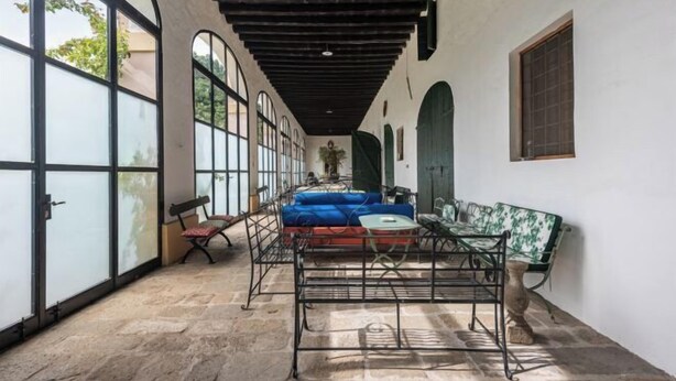 A spacious corridor with large windows, a bench, and a metal table with cushions. - Big Scuderia Country mansion_500sqm (San Pietro Viminario)