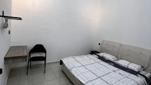 Ein Schlafzimmer mit einem Bett, einem Sessel, einem kleinen Tisch und einer Wand-Klimaanlage.