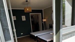 A room with two beds, a hanging light fixture, and a view of the outdoors. - Apartment Sana Klinik No 12 Balcony (Offenbach am Main)