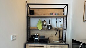 A compact kitchen with wooden cabinets, a black countertop, a sink, and a microwave. - Apartment Sana Klinik No 12 Balcony (Offenbach am Main)