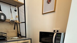 A compact kitchen with a microwave, a coffee machine, and a sink. - Apartment Sana Klinik No 12 Balcony (Offenbach am Main)