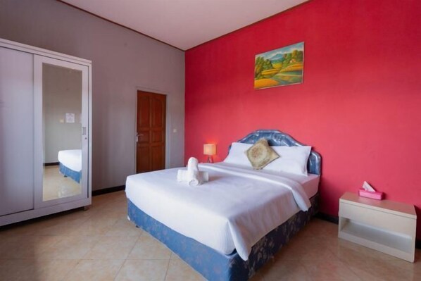 A hotel room with a bed, a nightstand, a wardrobe, and a painting on the wall. - Mountain View House Kintamani (Bali)