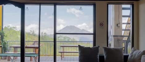 A room with a bed, a balcony with a table and chairs, and a view of a mountain.