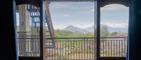 Une fenêtre donnant sur un paysage montagneux et un bâtiment doté d’un escalier.
